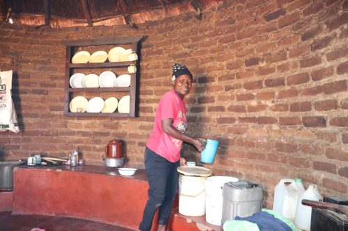 FOTO 3. Hilda in her kitchen fetching water